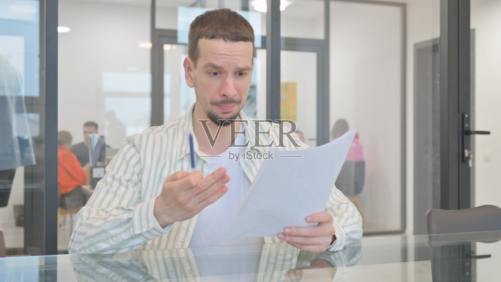 有创造力的年轻人阅读合同时感到不安照片摄影图片