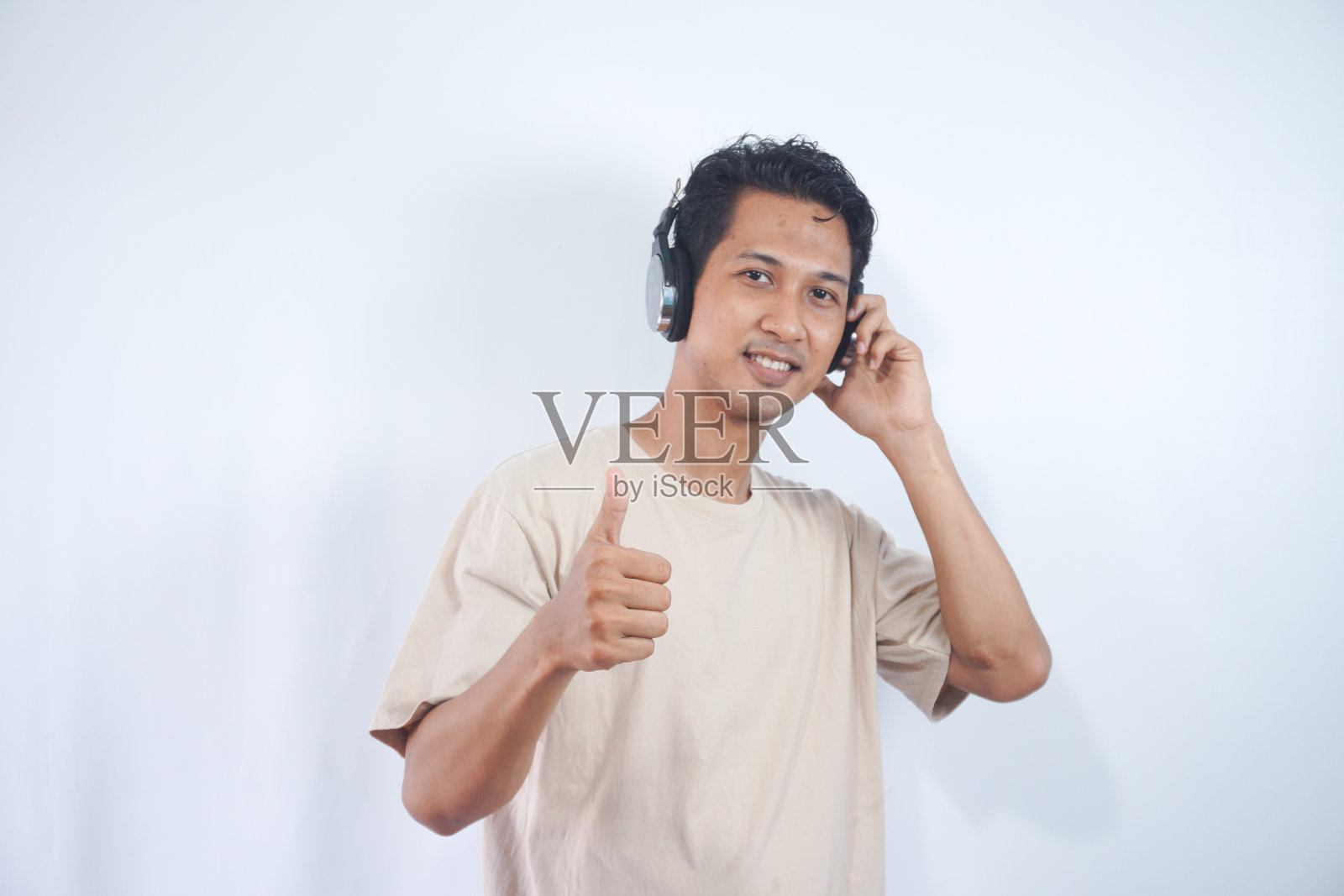 一名戴着耳机的亚洲男子露出敬畏、惊讶的微笑，喜欢这首歌的播放照片摄影图片