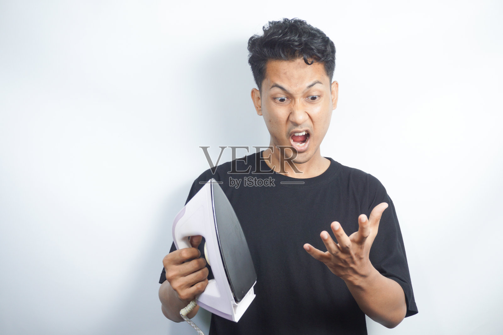 拿着熨斗的有趣年轻人。照片摄影图片