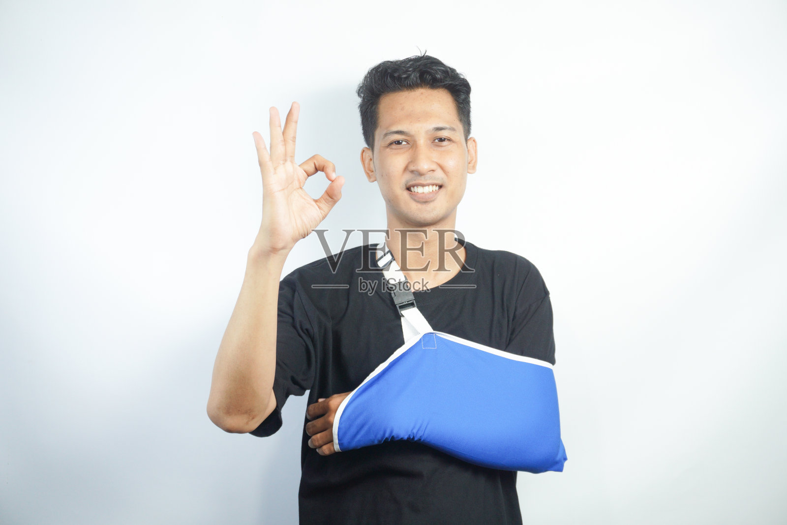 年轻的白人男子的肖像与夹板手臂后的事故或创伤。男性患者用绷带或吊带包扎手或肩，与受伤作斗争有康复。恢复和康复。照片摄影图片