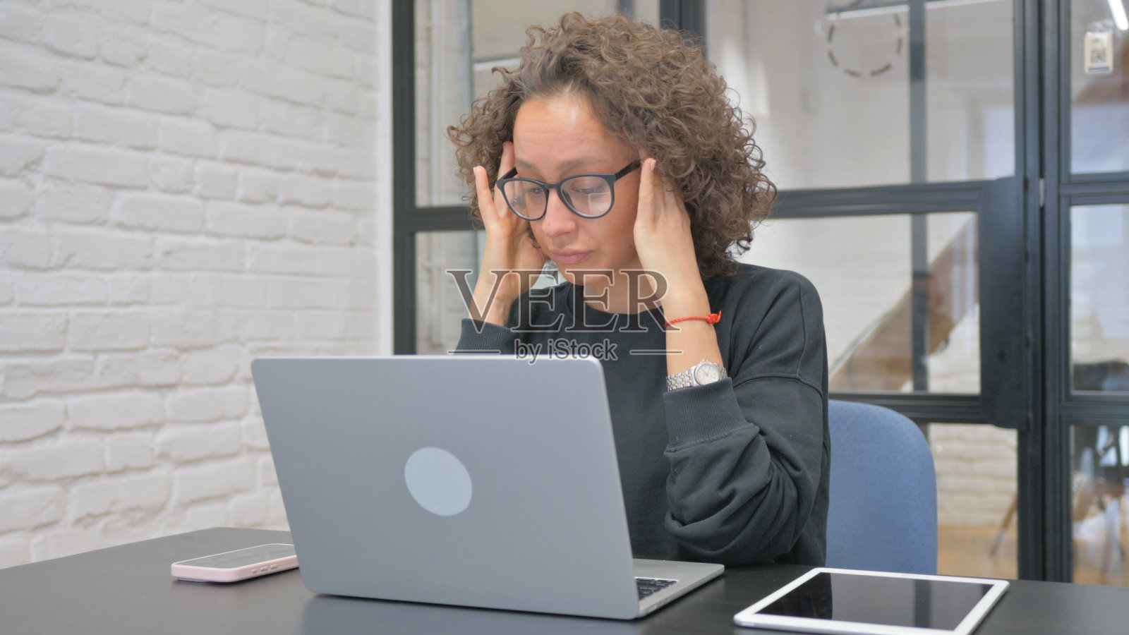 工作中头痛的西班牙裔女人照片摄影图片