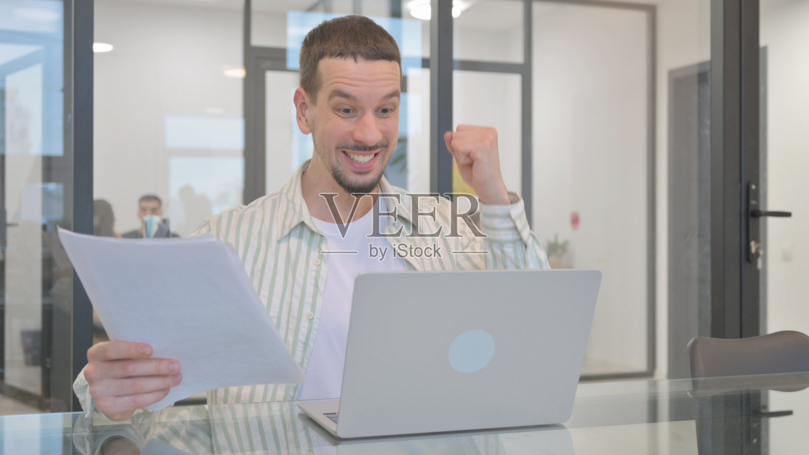 创意年轻人一边用笔记本电脑和文件一边庆祝照片摄影图片