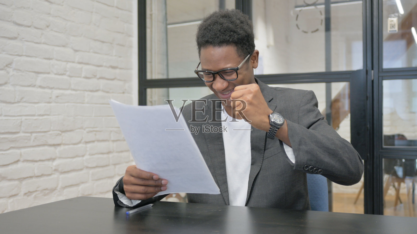 非洲青年一边阅读文件一边庆祝照片摄影图片