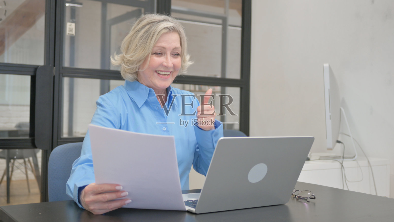 老年妇女在笔记本电脑和文件上庆祝工作照片摄影图片