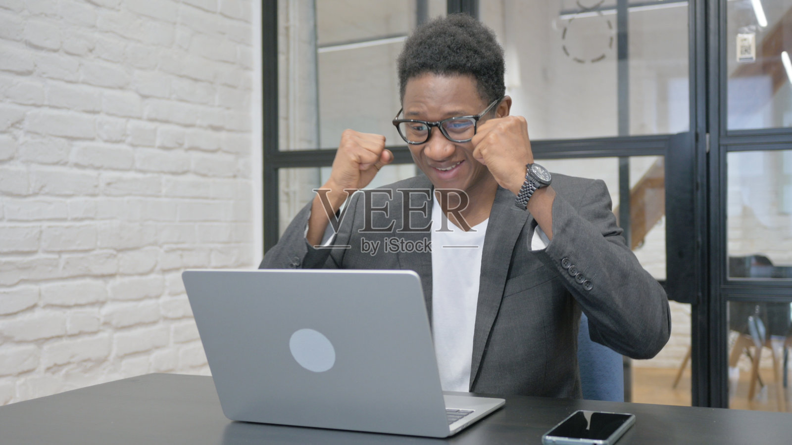 非洲年轻人用笔记本电脑庆祝成功照片摄影图片