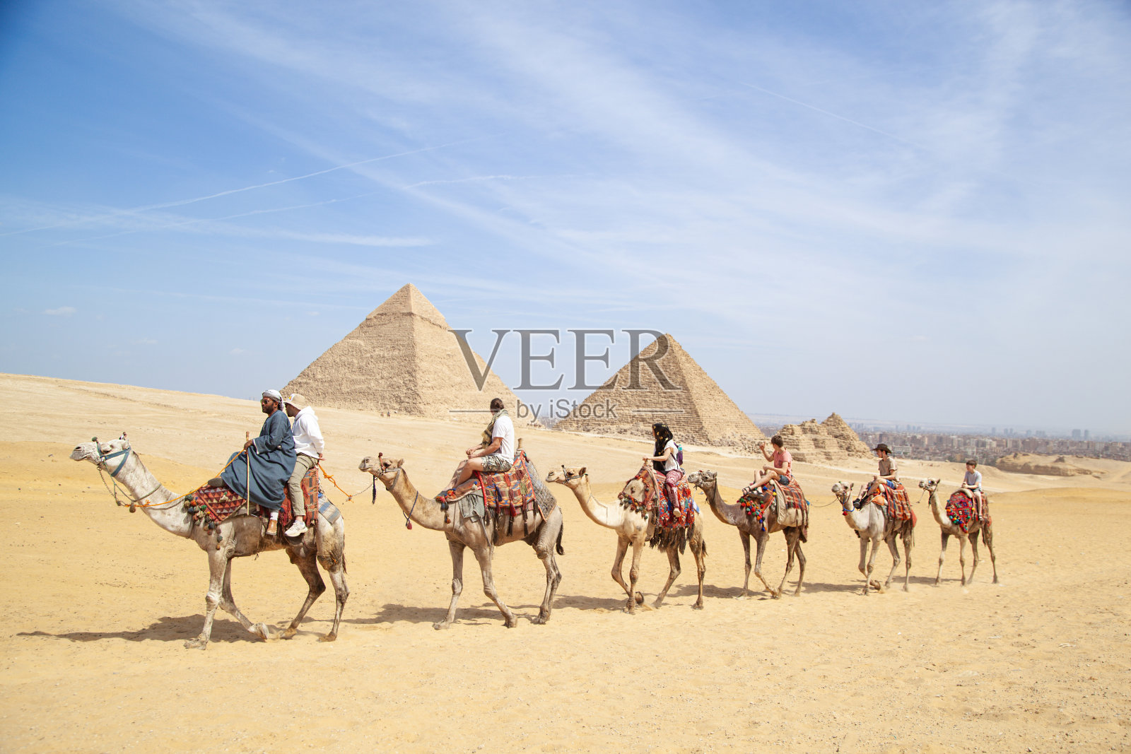 游客在埃及沙漠骑骆驼参观开罗金字塔照片摄影图片