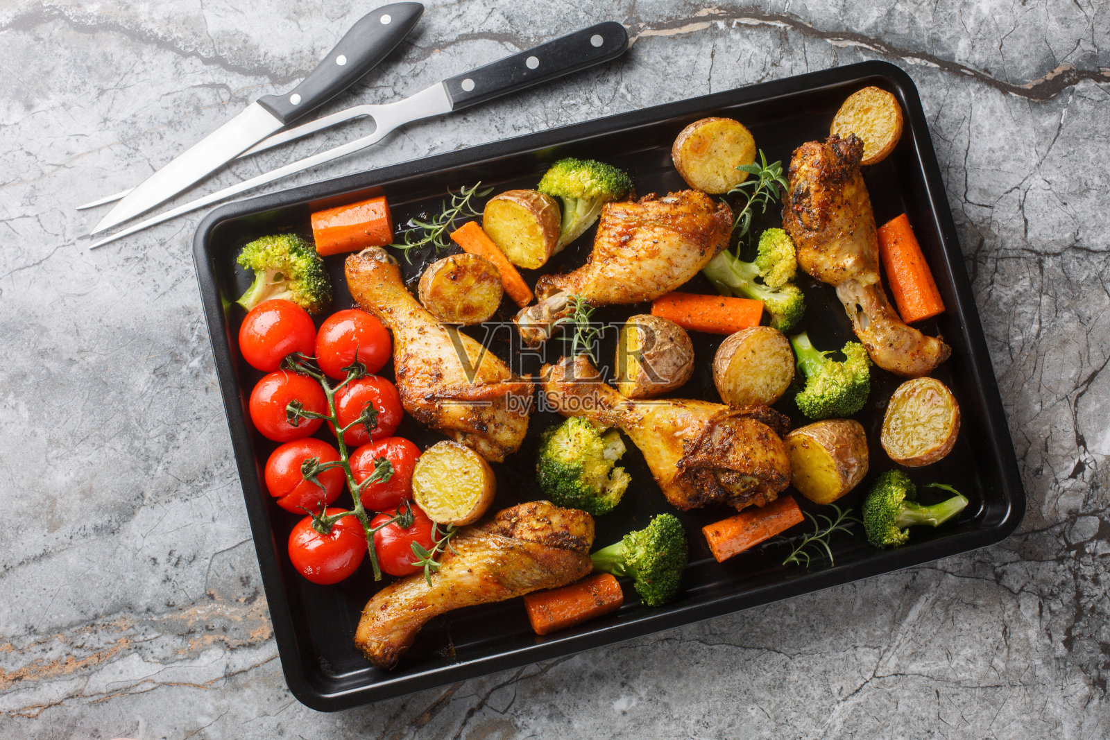 烤箱烤鸡腿与新鲜出炉的蔬菜在烤盘上的特写。水平俯视图照片摄影图片