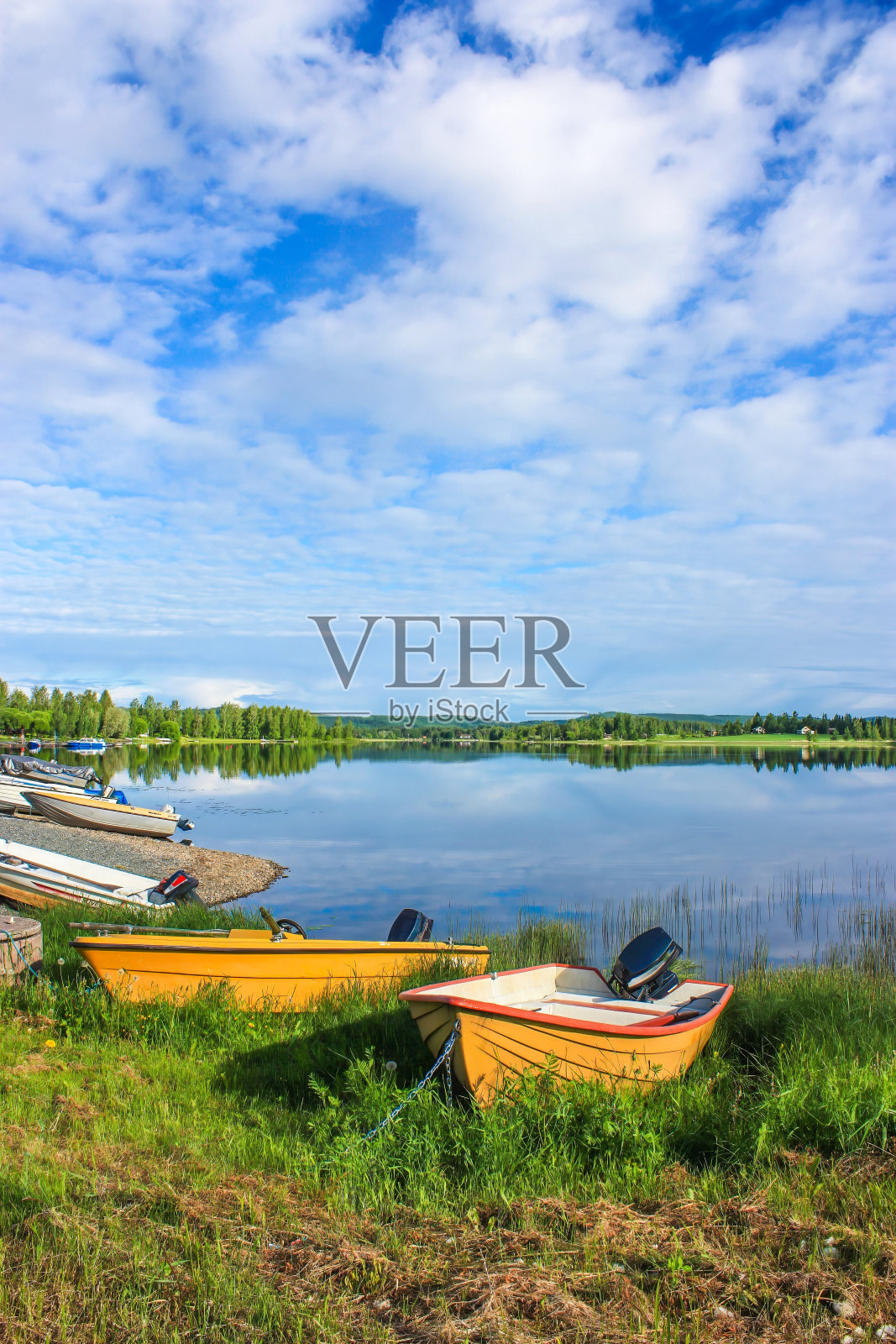 在阳光明媚的日子里，宁静的湖边有小船。照片摄影图片