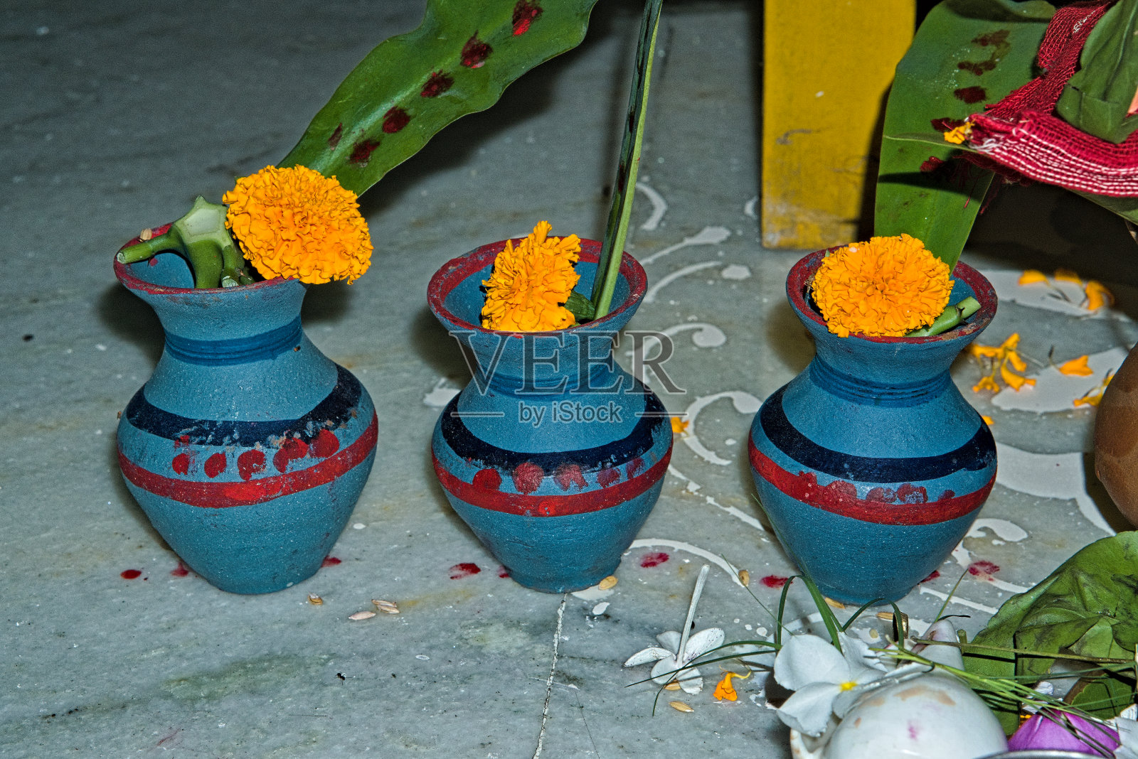 在印度马纳萨普日(Manasa Puja)时,在地板上摆放鲜花的彩色陶罐。照片摄影图片