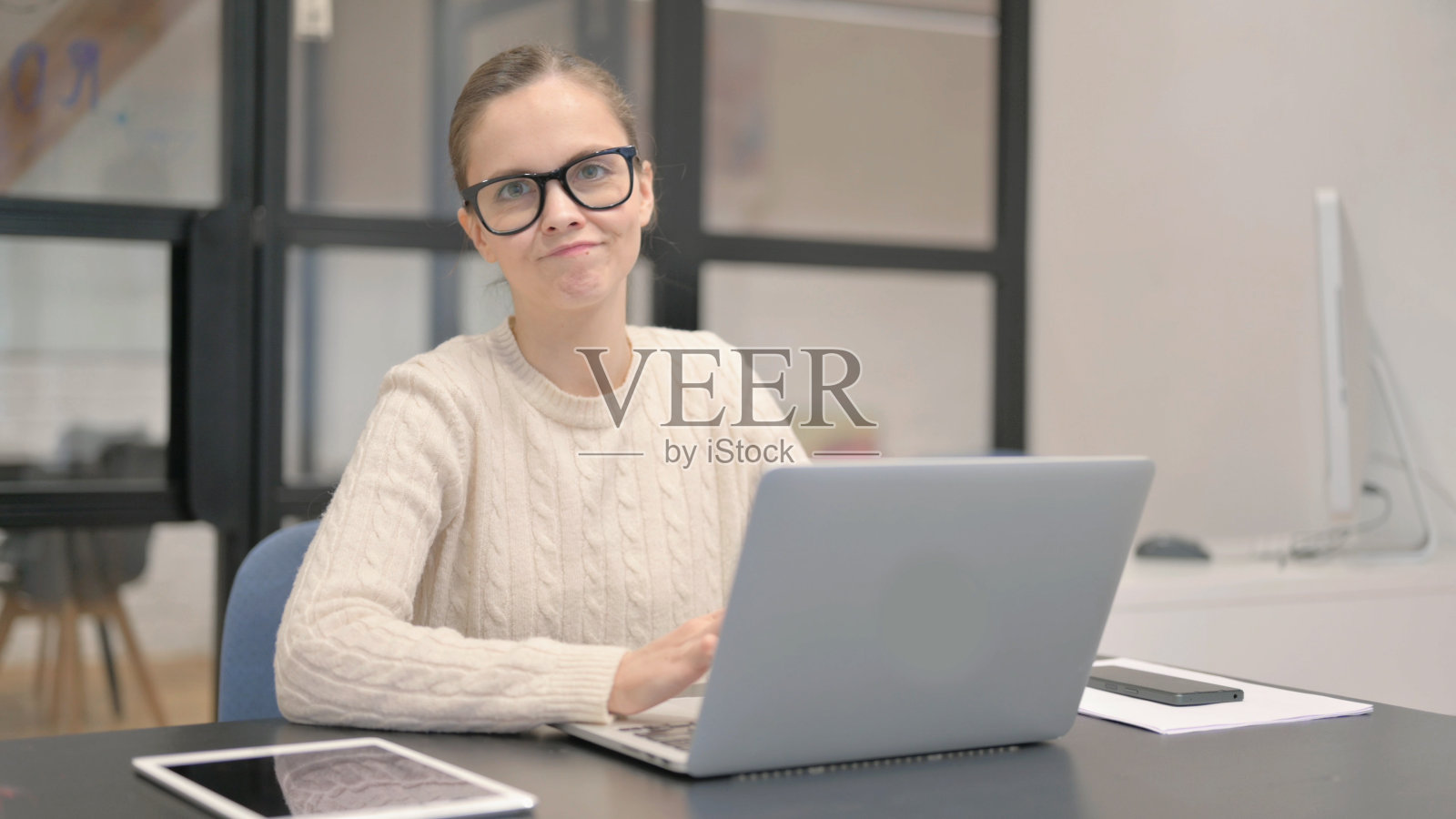 拒绝年轻女子一边用笔记本电脑一边看相机照片摄影图片