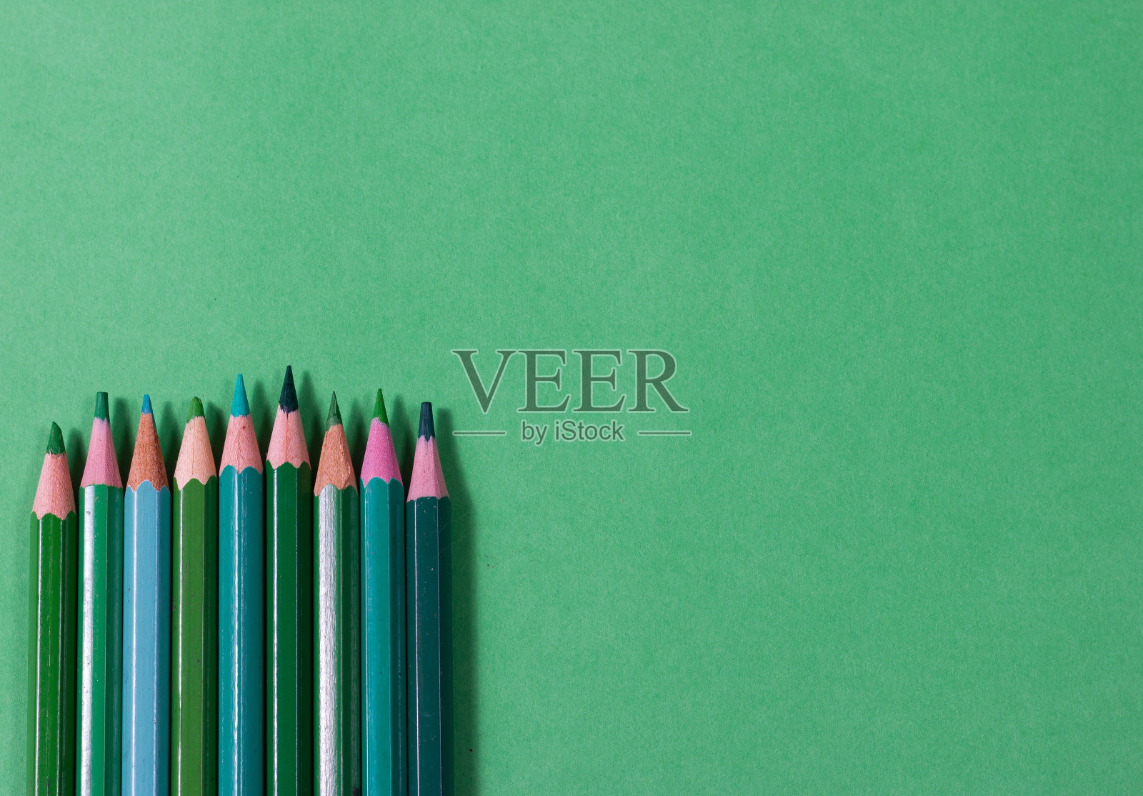 绿色的木制彩色铅笔在相同的背景。回到学校。学习用品。照片摄影图片