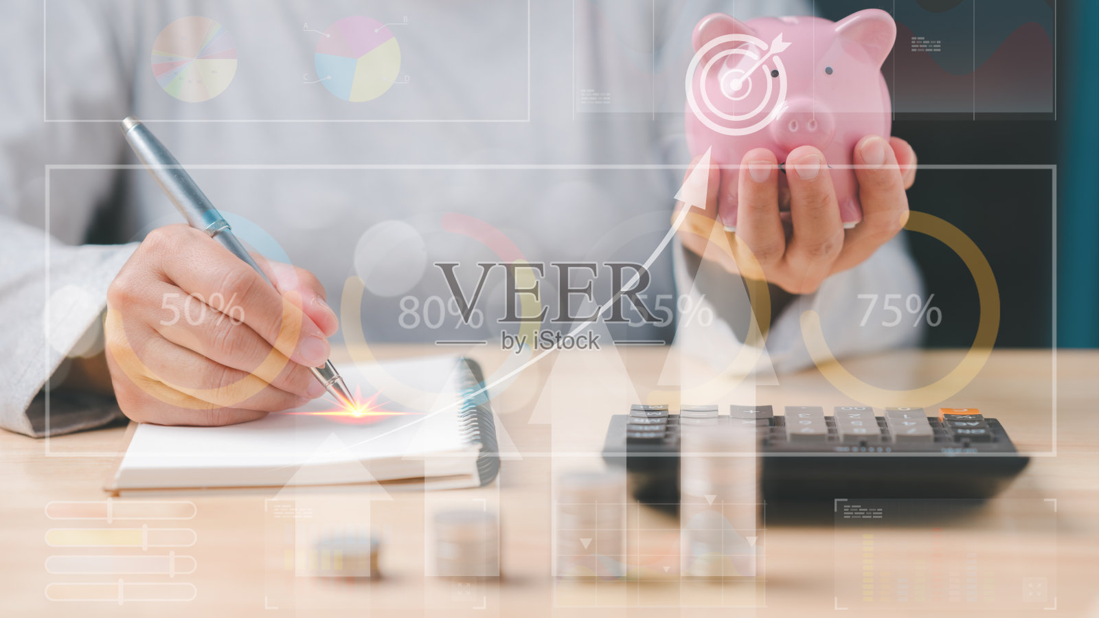 一个人在笔记本上写东西，桌上放着一个粉红色的扑满。商业经济增长图照片摄影图片