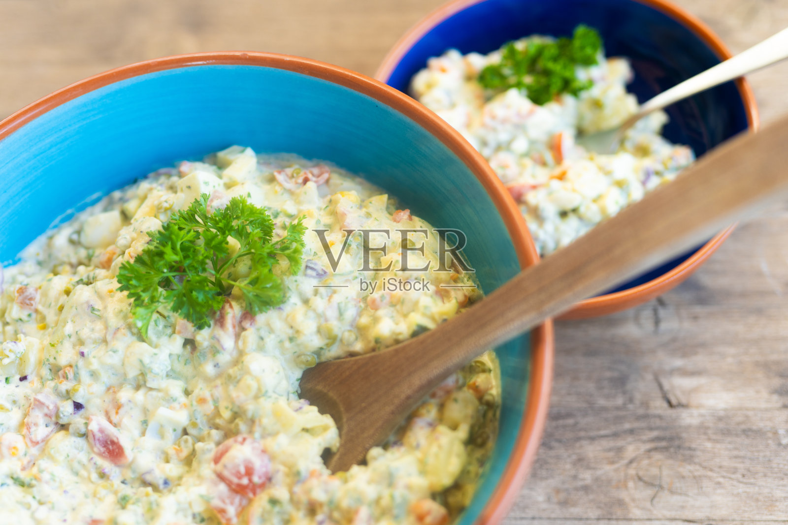 两个蓝色的马洛昆陶瓷碗，每个都装满了健康的土豆沙拉和蔬菜照片摄影图片