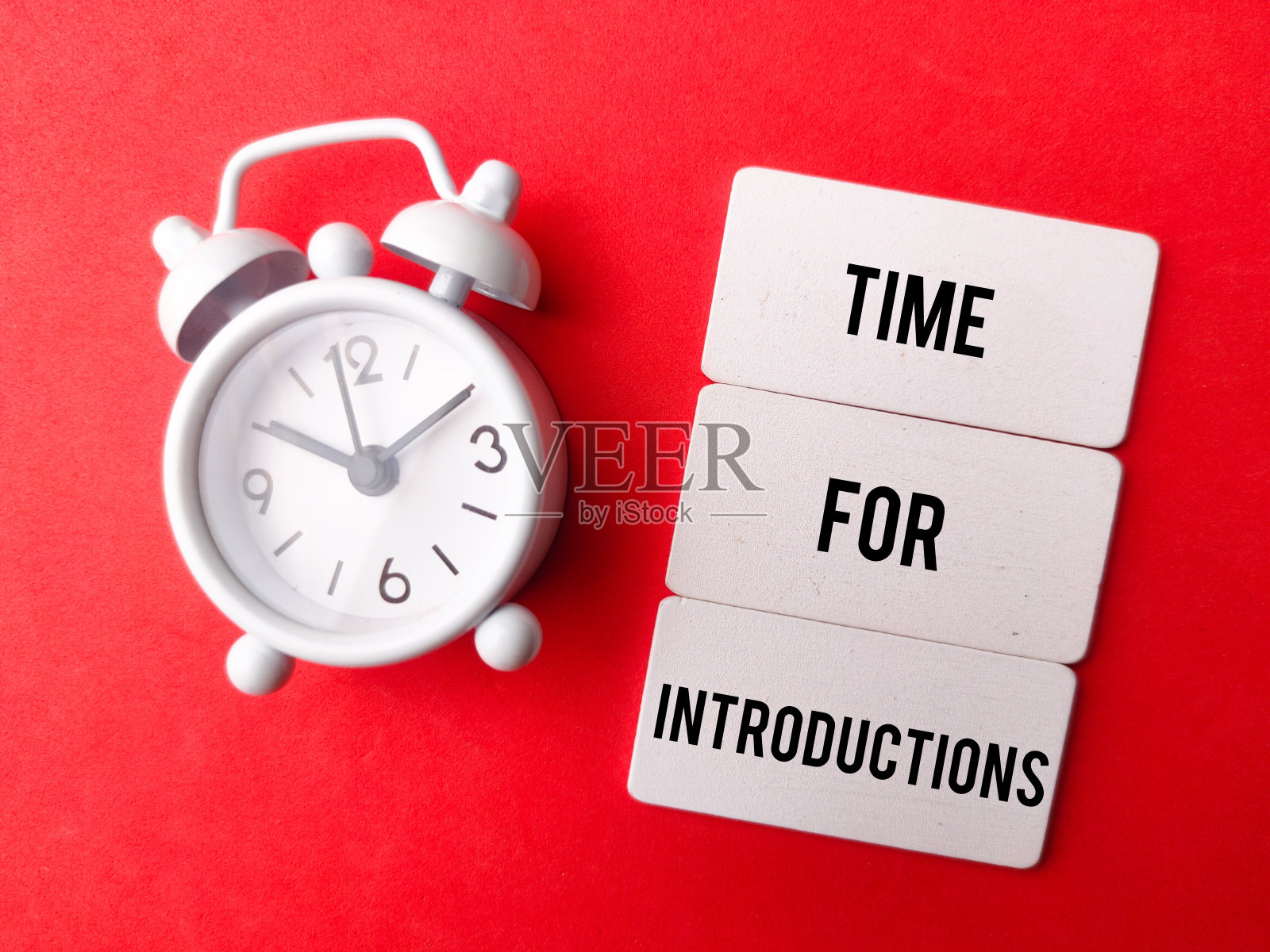 闹钟和木板，红色背景上写着“介绍时间”。经营理念。照片摄影图片