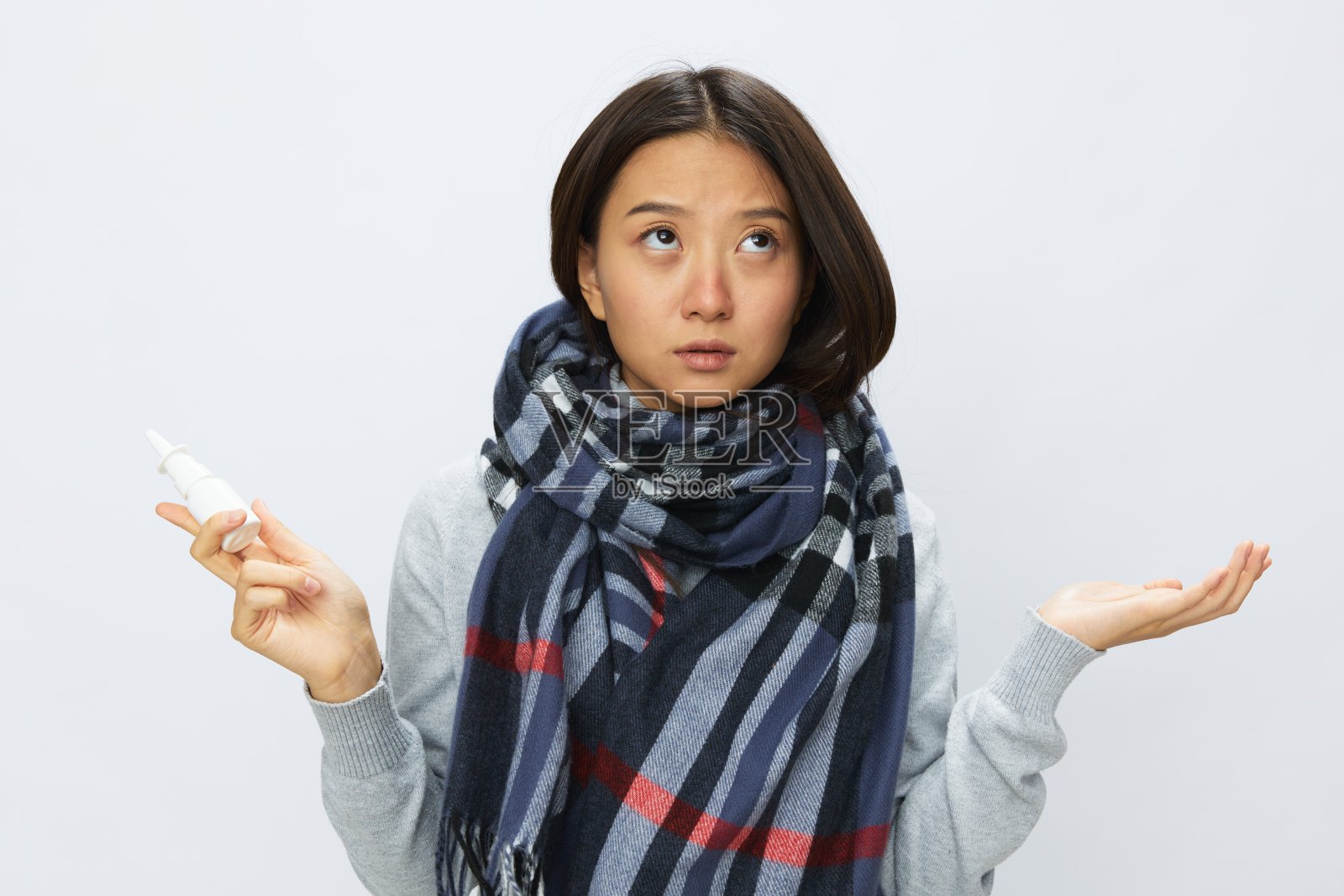 亚洲女性感冒鼻塞拿着过敏和covid - 19病毒鼻喷雾剂，白色背景的喉咙痛照片摄影图片