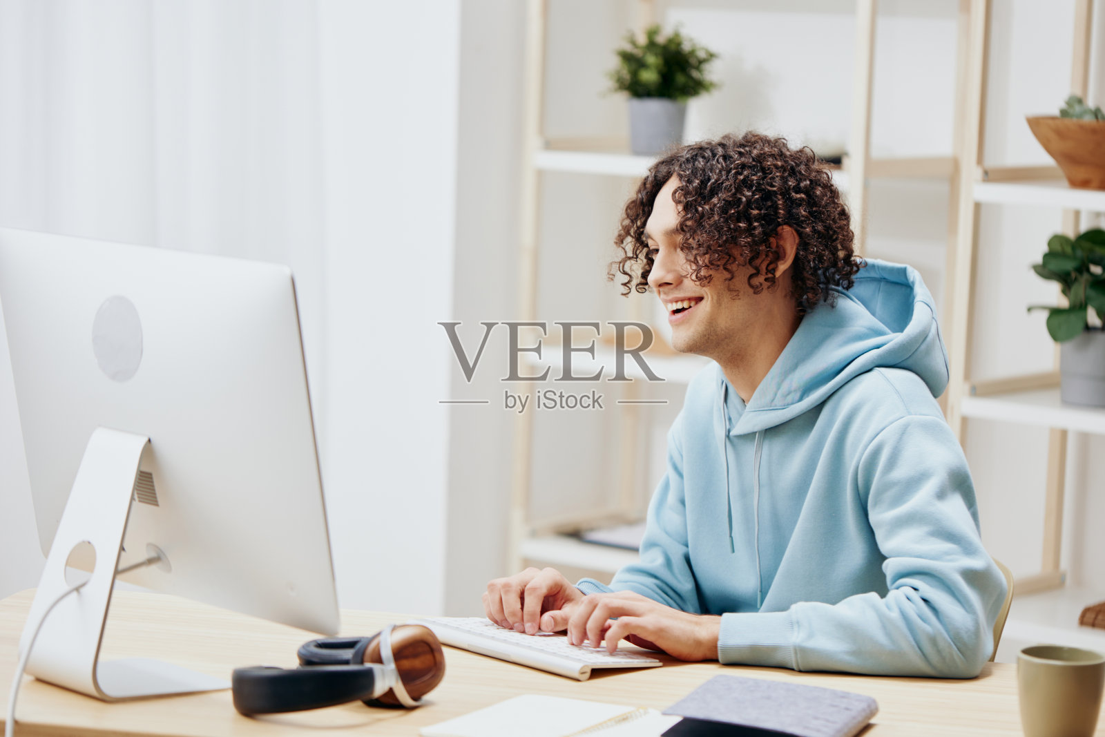 帅哥坐在电脑前的桌子上，自由从事技术工作照片摄影图片