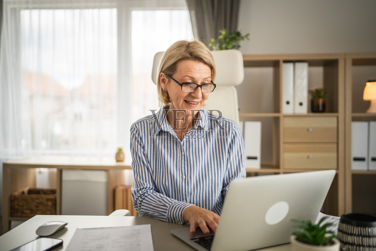 成熟的女商人在办公室工作时使用笔记本电脑照片摄影图片