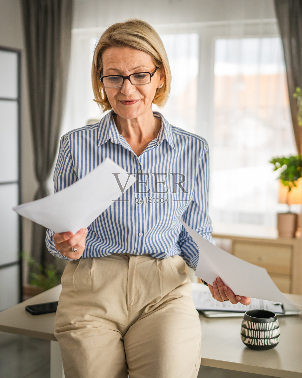成熟的女人在办公室读着合同文件，开心的笑了照片摄影图片