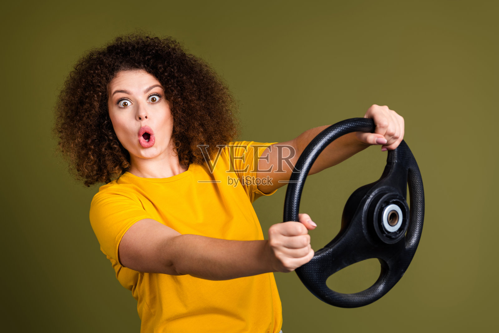 照片中，年轻的卷发女子开着男友的车，在卡其色的背景上，有那么多马力照片摄影图片