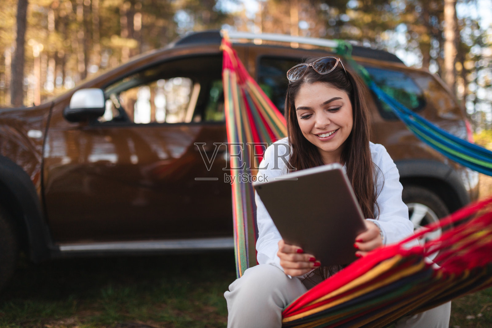 微笑的年轻女子在户外放松时使用平板电脑照片摄影图片