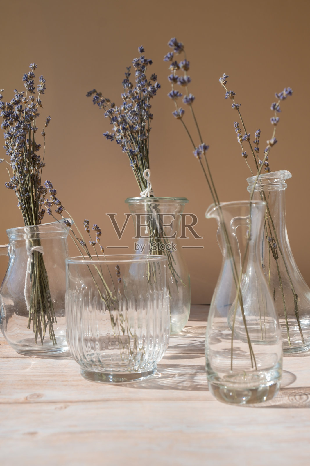 玻璃盘子里放着薰衣草花。米色背景上的干草本花。最小静物生态概念。展示薰衣草精华化妆品的理想场所照片摄影图片