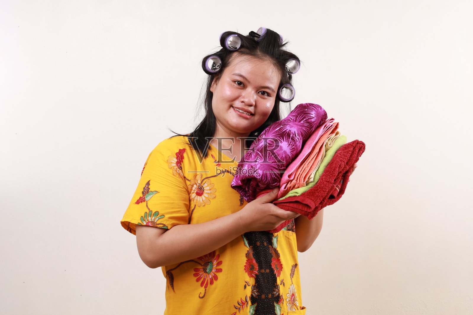 快乐的亚洲女管家站着拿着衣服照片摄影图片