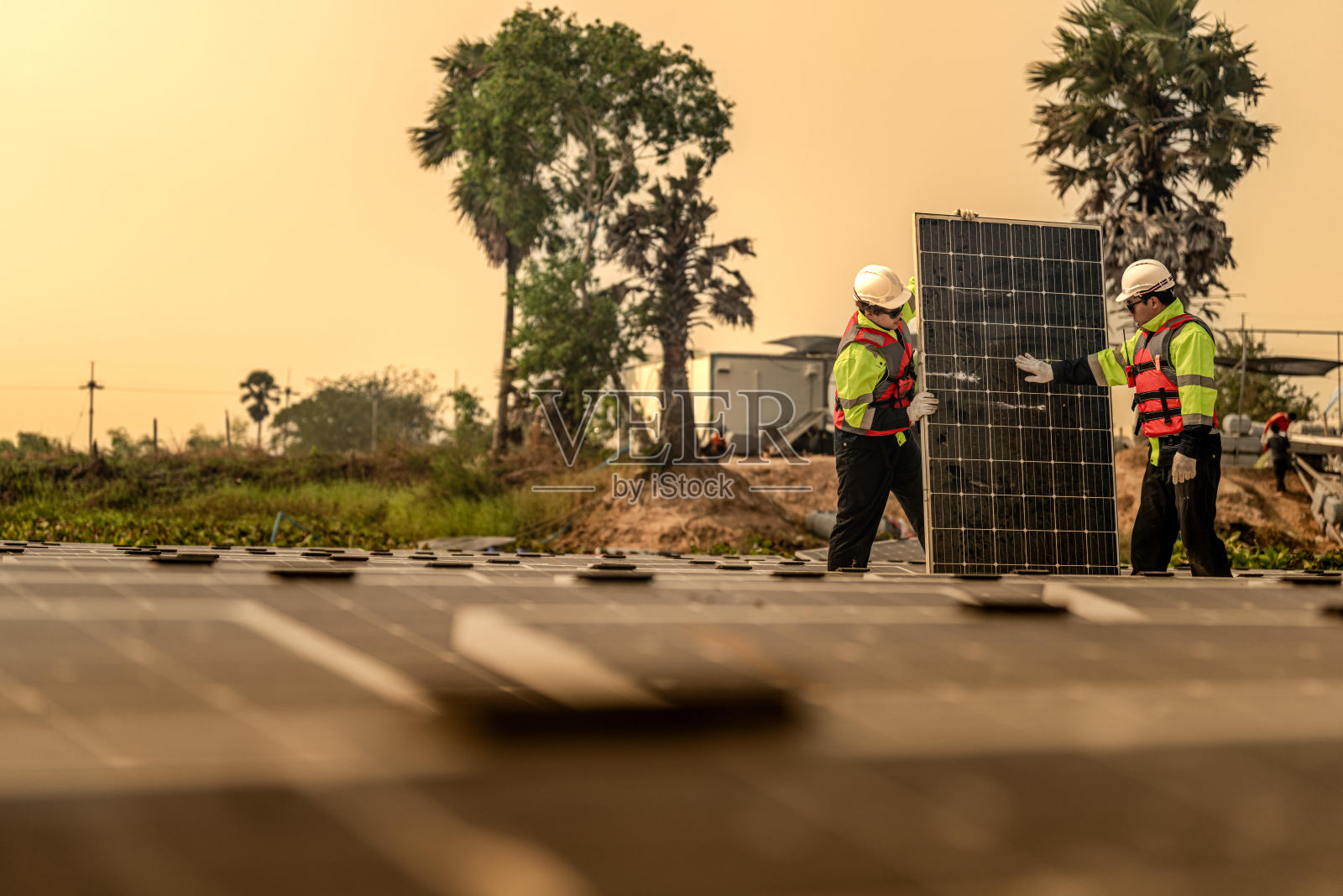 光伏工程师研究浮动光伏。工人检查和修理漂浮在水面上的太阳能电池板设备。工程师在湖面上安装浮动太阳能板平台系统。照片摄影图片