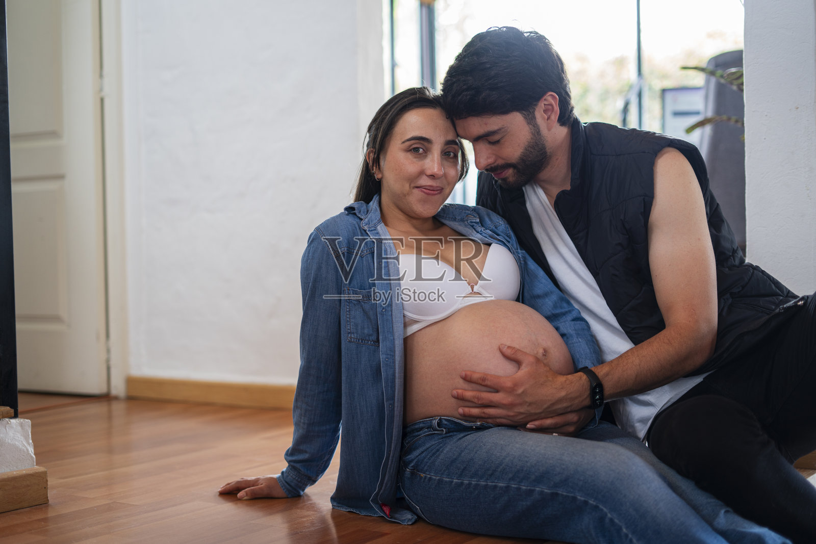 拉丁异性恋夫妇享受独处的时光，在生产前爱抚他们的肚子，加强他们作为夫妻的联系照片摄影图片