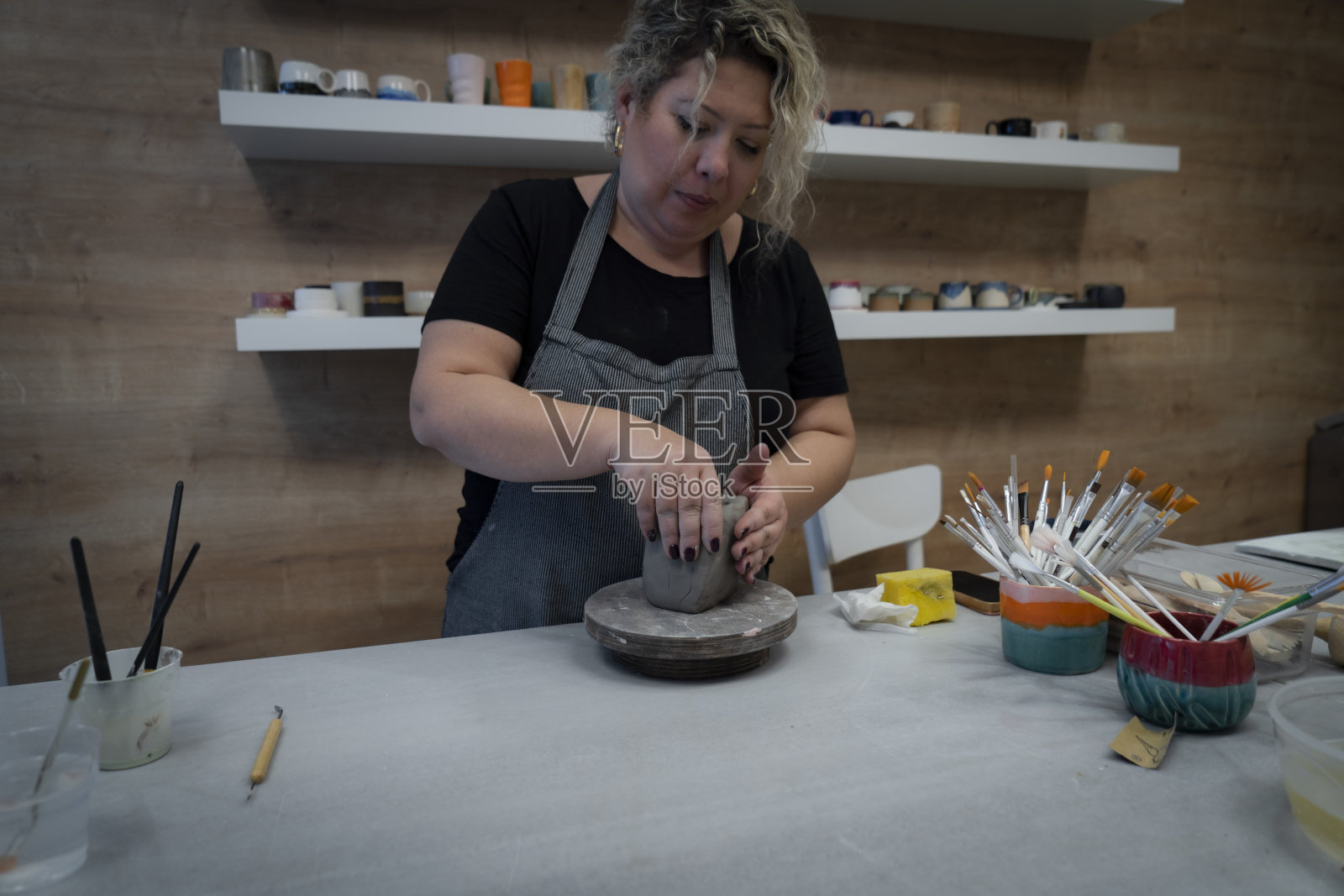 女陶工在陶轮上用湿粘土制成的围裙状花瓶里照片摄影图片