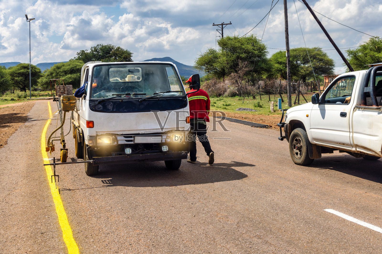 非洲人正在修理和维护高速公路上褪色的道路标志，为交通安全重新粉刷黄色标志照片摄影图片