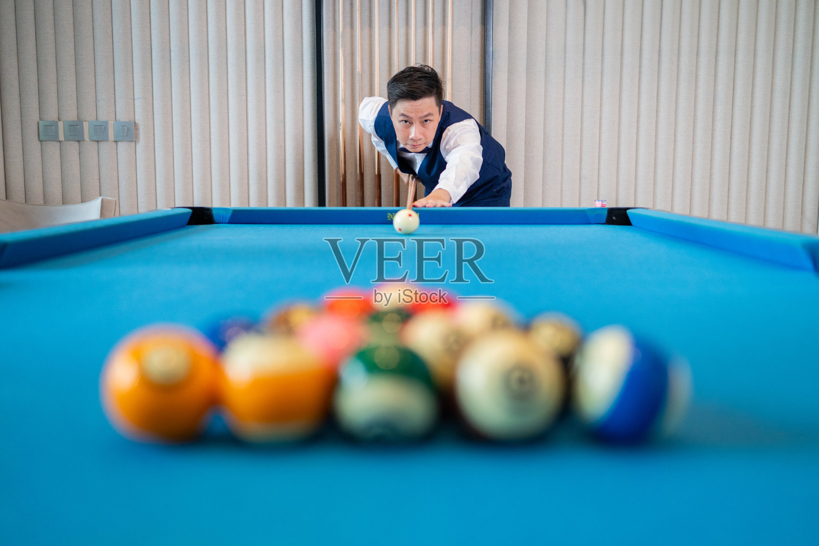 认真的台球运动员在蓝色的桌子上瞄准照片摄影图片