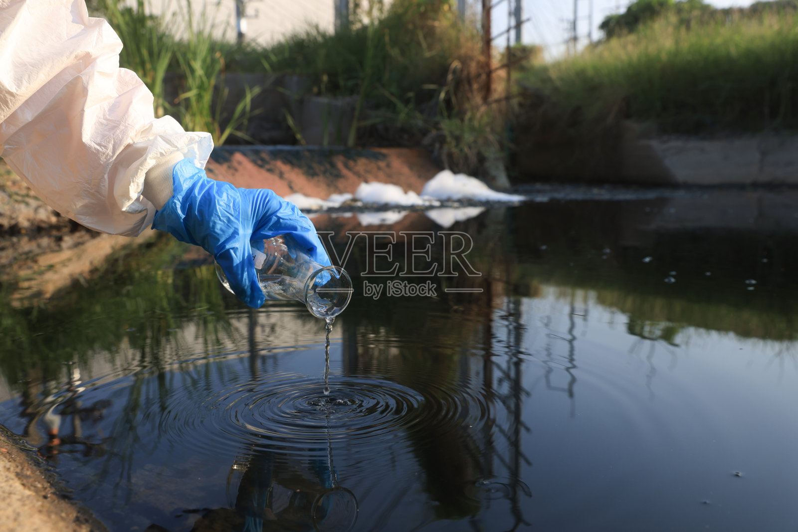 科学家或环境工作人员从工厂收集废水样本，生态和环境概念污染，从工业园区采样废水照片摄影图片