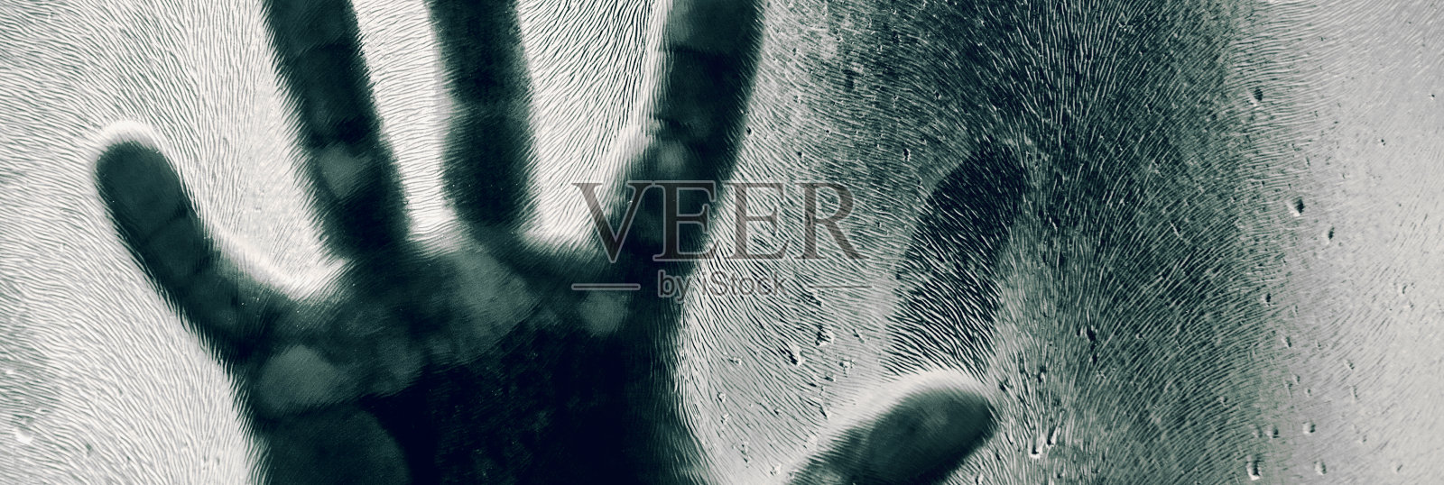 他的手压在磨砂玻璃上。一个男人的影子后面的哑光玻璃模糊的手和身体软焦点。照片摄影图片