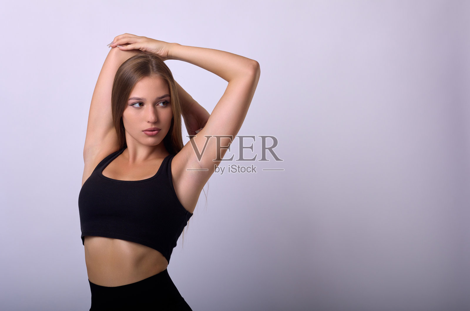 身材苗条、年轻漂亮、长发、黑色短背心的模特举起了手照片摄影图片