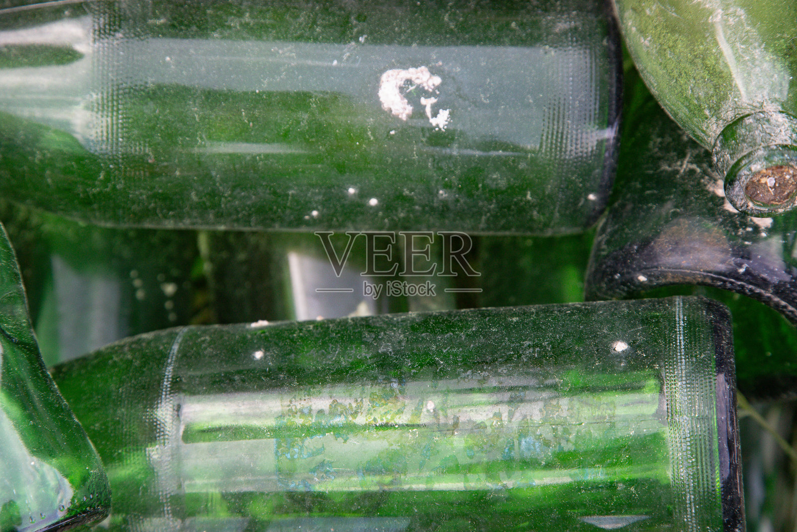 随机留下的空的、用过的和脏的绿色玻璃瓶的特写。抽象背景，概念回收、再利用、回收。照片摄影图片