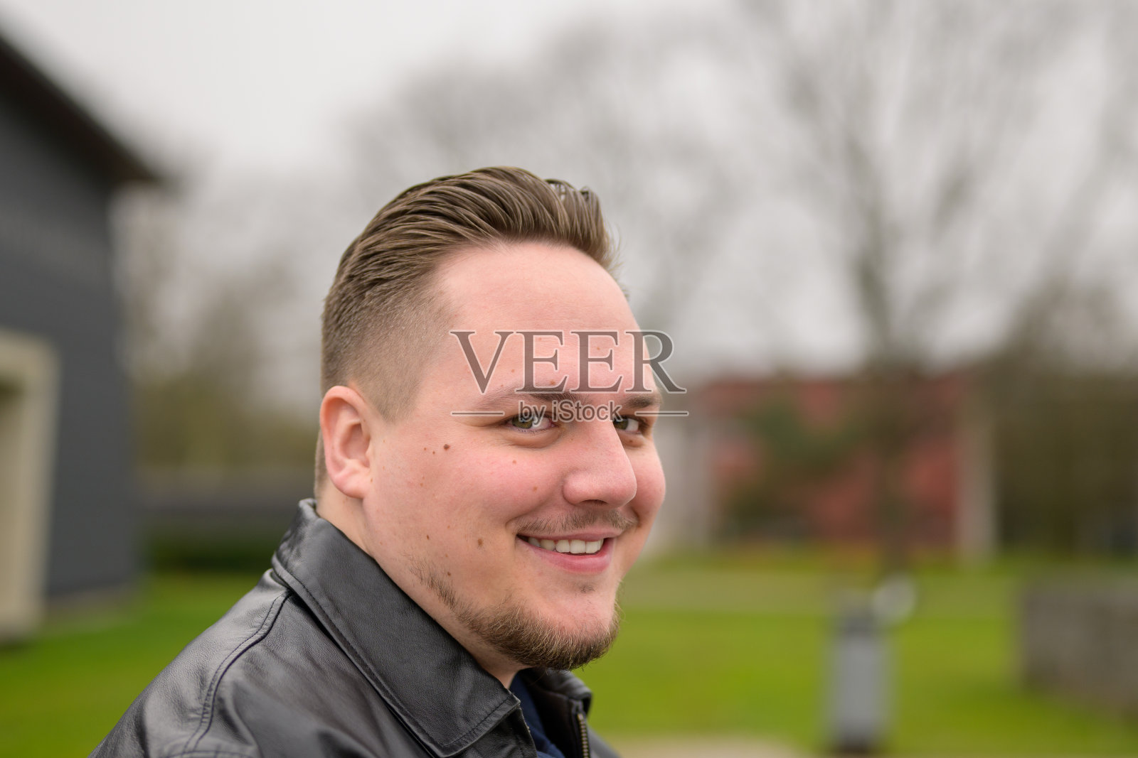 一个20多岁的年轻英俊男子站在公园外面的特写照片摄影图片