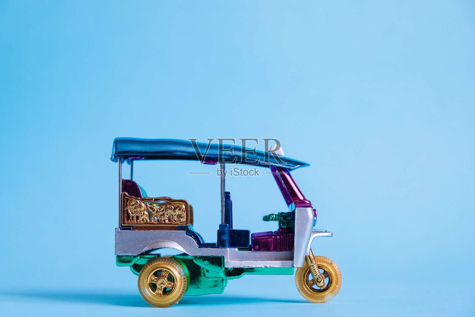 模型玩具嘟嘟车孤立在蓝色背景。泰国曼谷的传统出租车。纪念品照片摄影图片