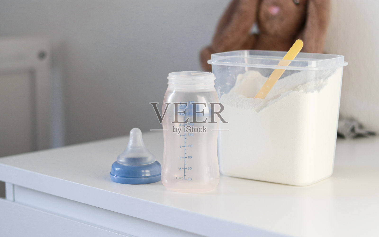 干粉配方奶粉喂养婴儿在一个黄色塑料勺和空喂养瓶罐头照片摄影图片