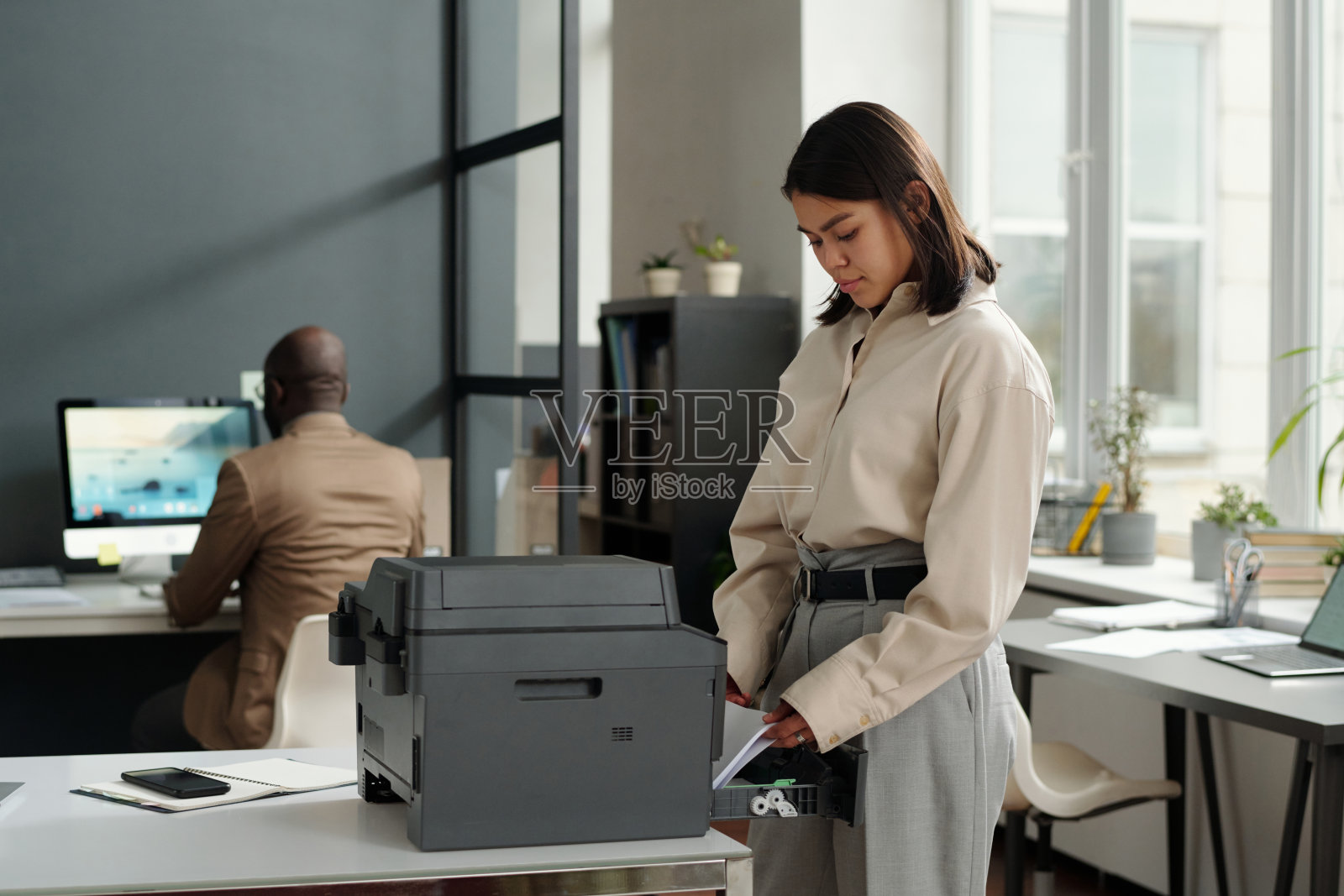 年轻的棕发女商人将纸张放入复印机照片摄影图片