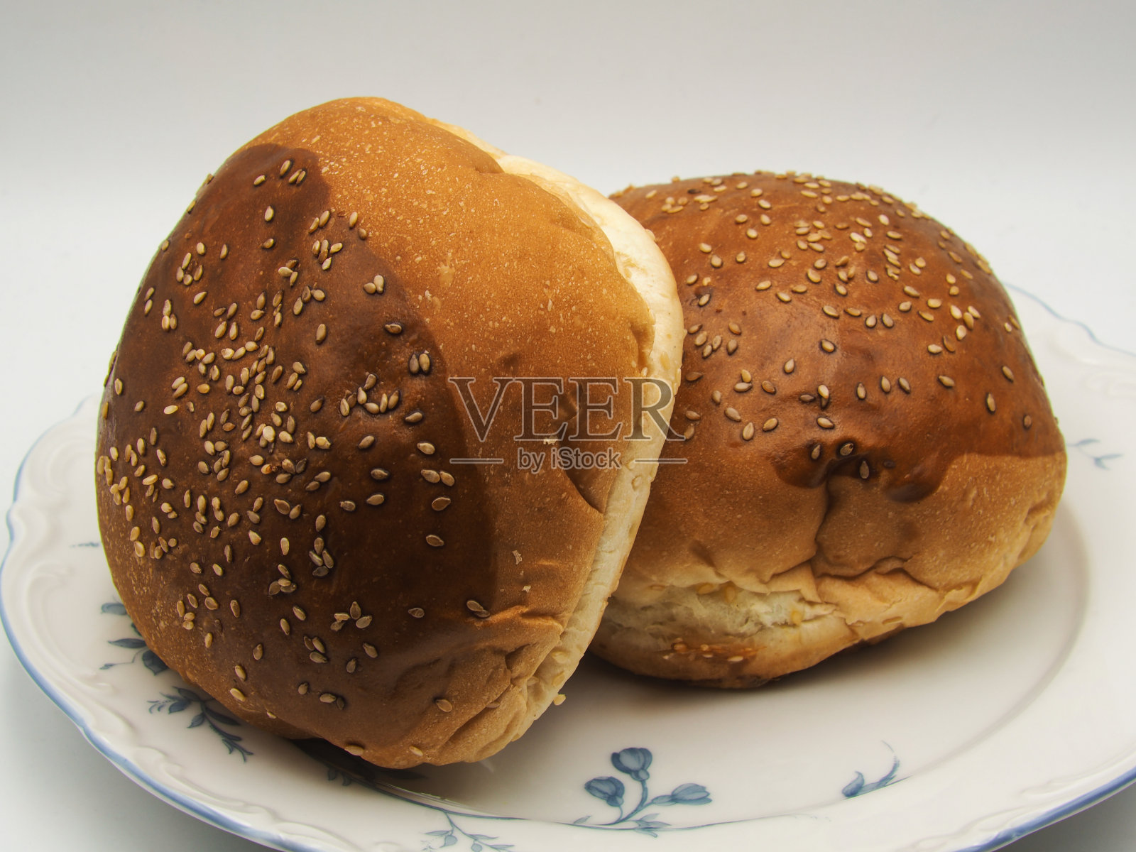 新鲜的汉堡面包和芝麻放在盘子里，背景是白色的照片摄影图片