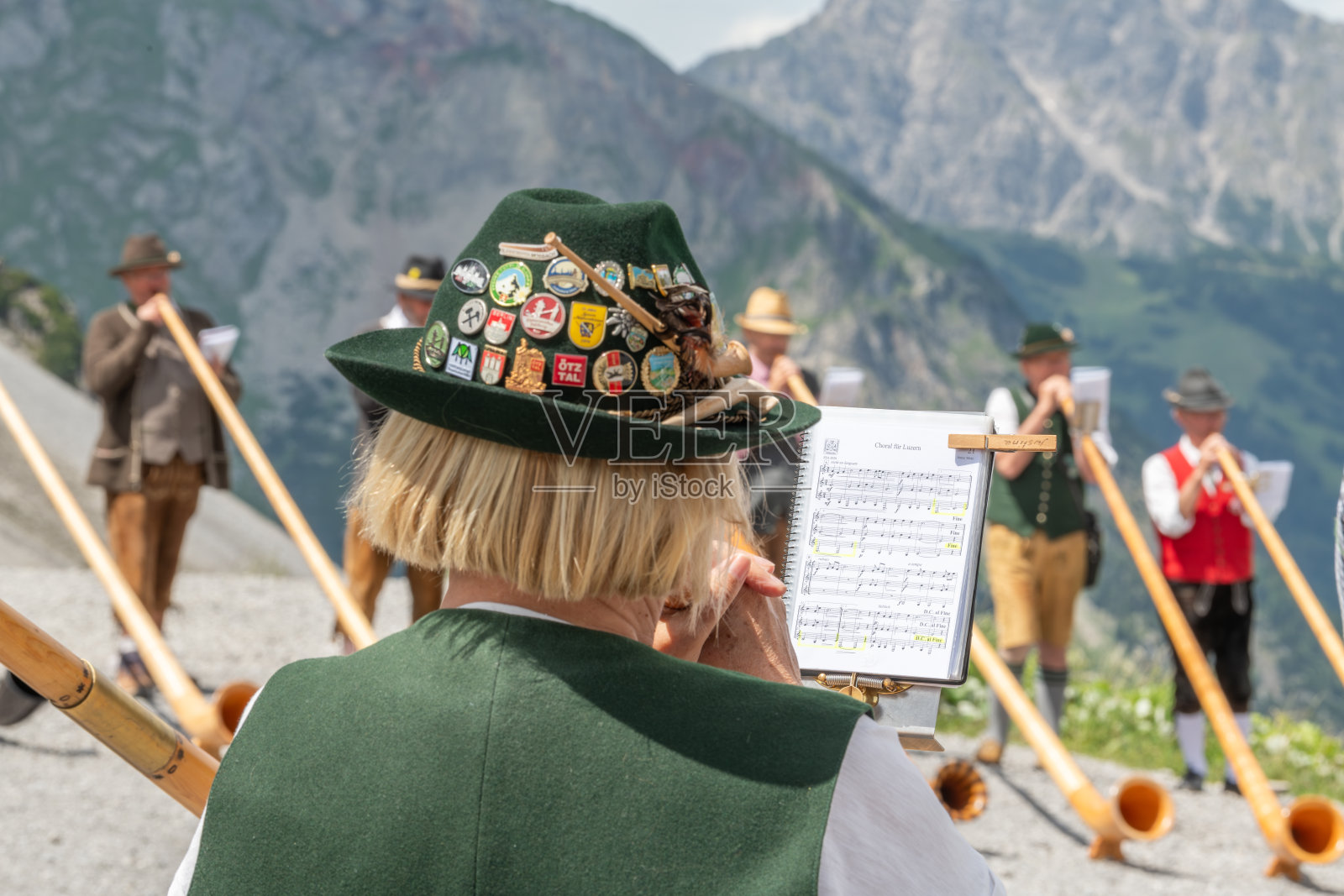 身穿奥地利传统服装的男女长号手在奥地利的l<s:1>涅尔泽山湖演奏。背景是山坡。球员的近景。2023年7月8日,奥地利布兰德照片摄影图片