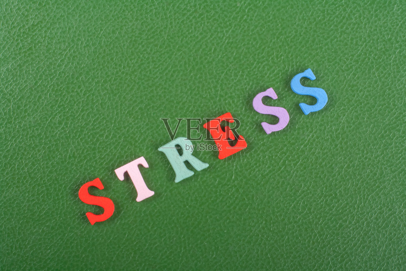 绿色背景上的强调词由彩色abc字母表块木制字母组成，为广告文字提供复制空间。学习英语的理念。照片摄影图片