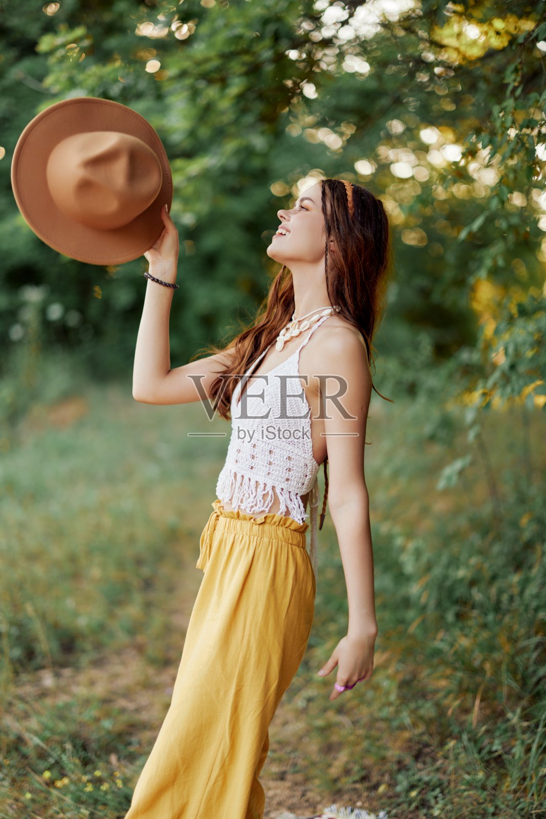 一个年轻的嬉皮女人在秋天的大自然中欢快地跳舞，真诚地微笑。节约消费和自我保健的观念照片摄影图片