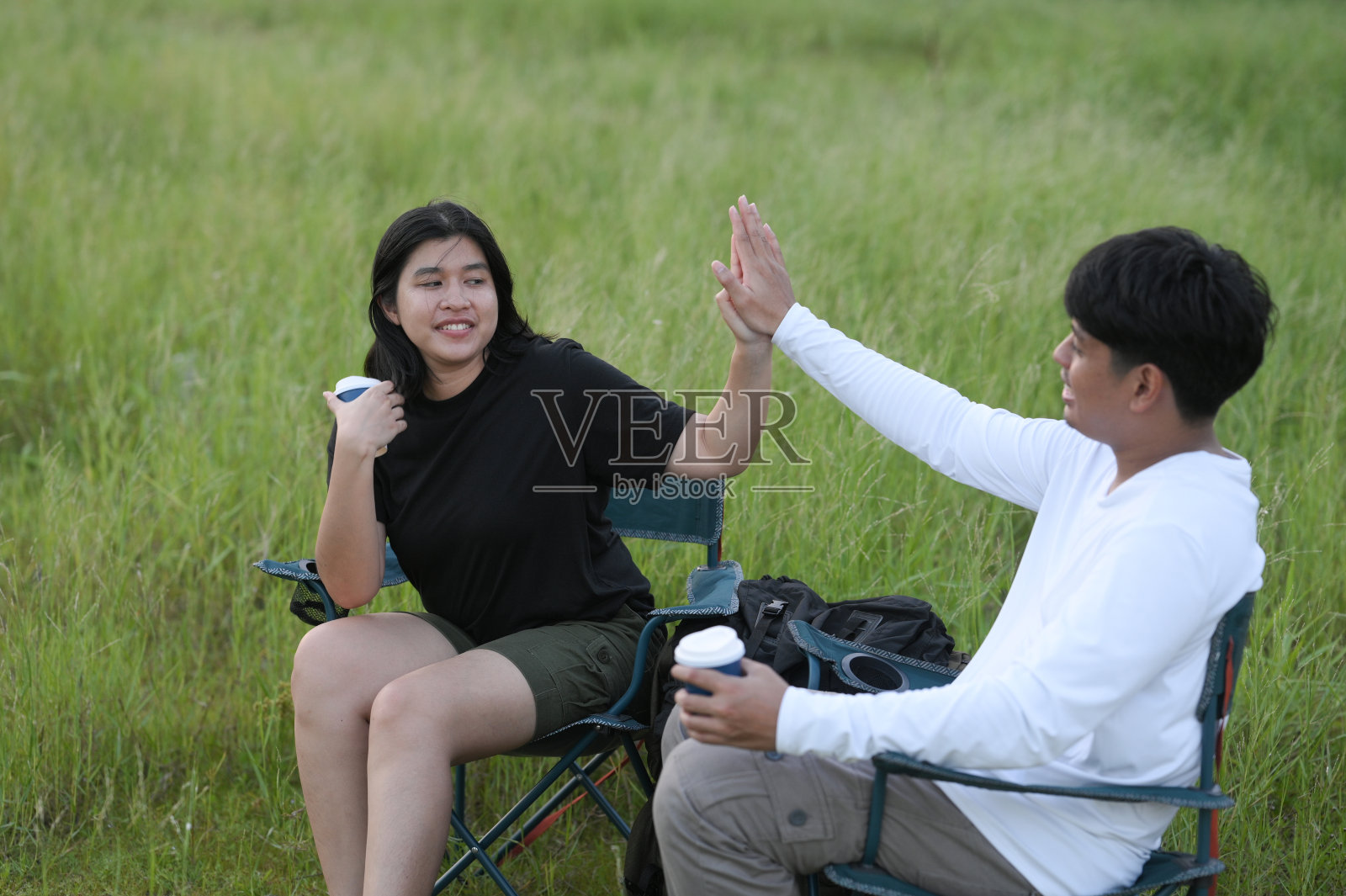 一个英俊的年轻人和一个美丽的年轻女子在露营度假期间坐着放松。照片摄影图片