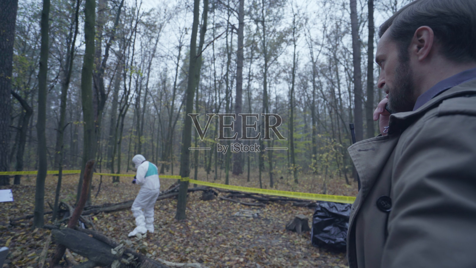 严肃的警探一边打电话一边看着法医专家收集证据照片摄影图片