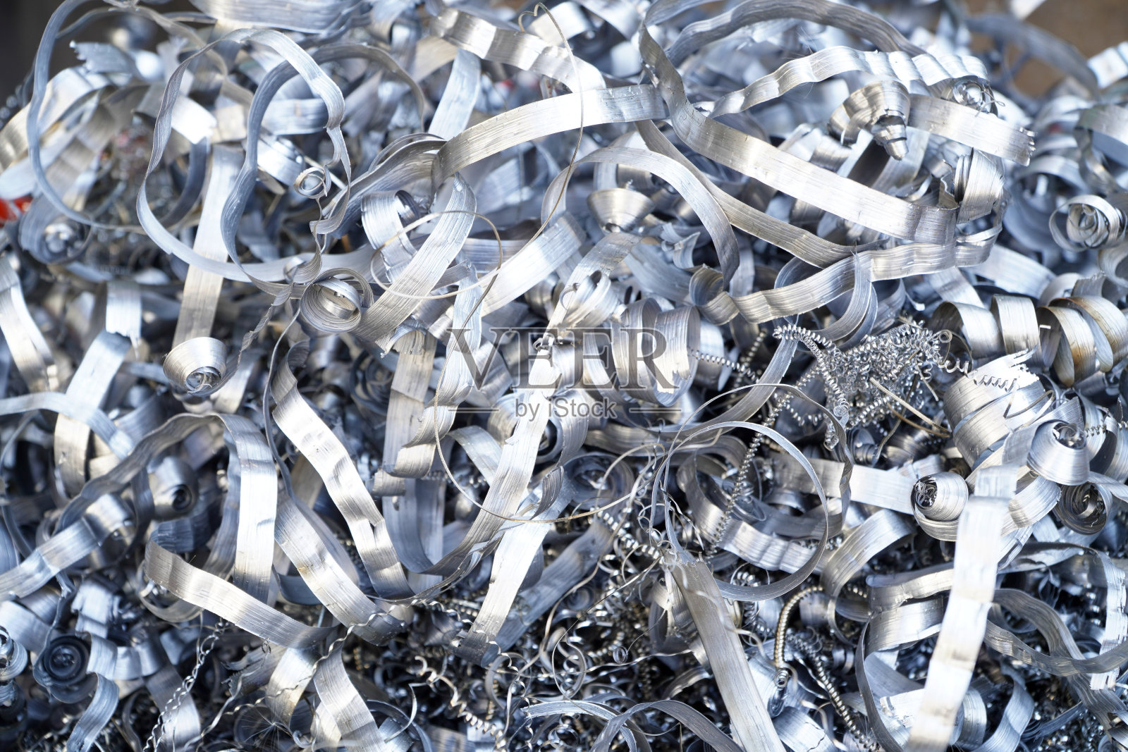 钢铁废料回收。在数控车床上加工金属零件后产生的铝屑。特写扭曲螺旋钢刨花。小粗糙度锐度，照片摄影图片