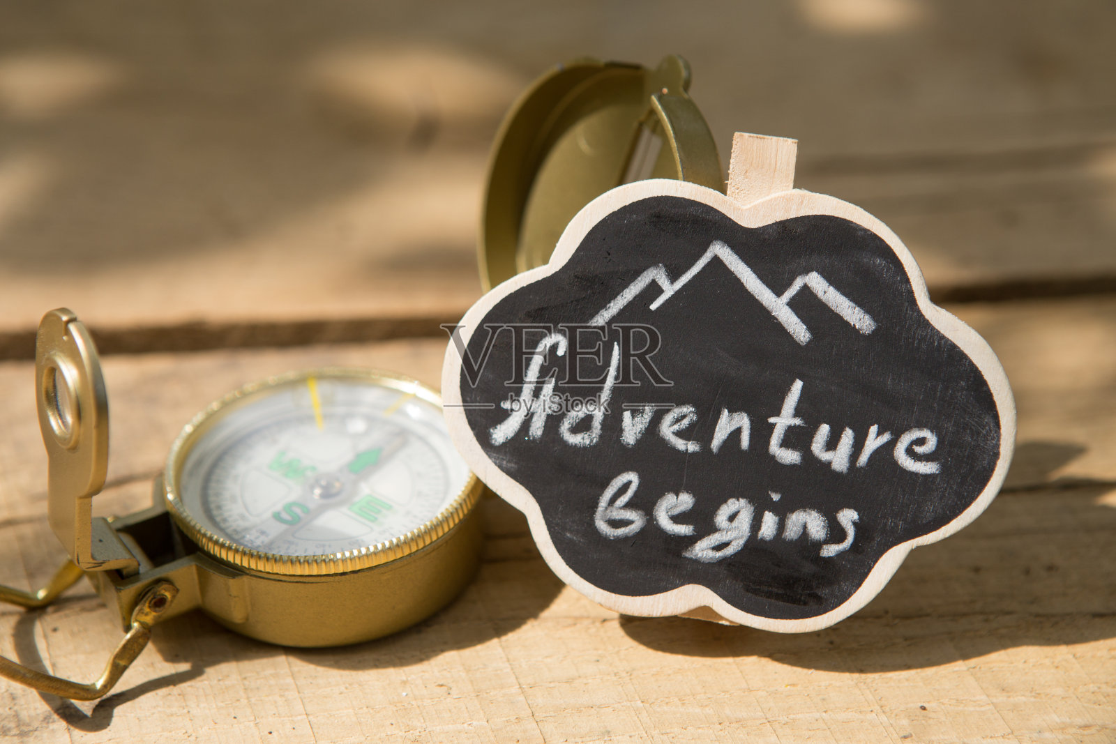 冒险开始了，用指南针写在一个小牌子上。开始你的旅行概念。木制背景照片摄影图片