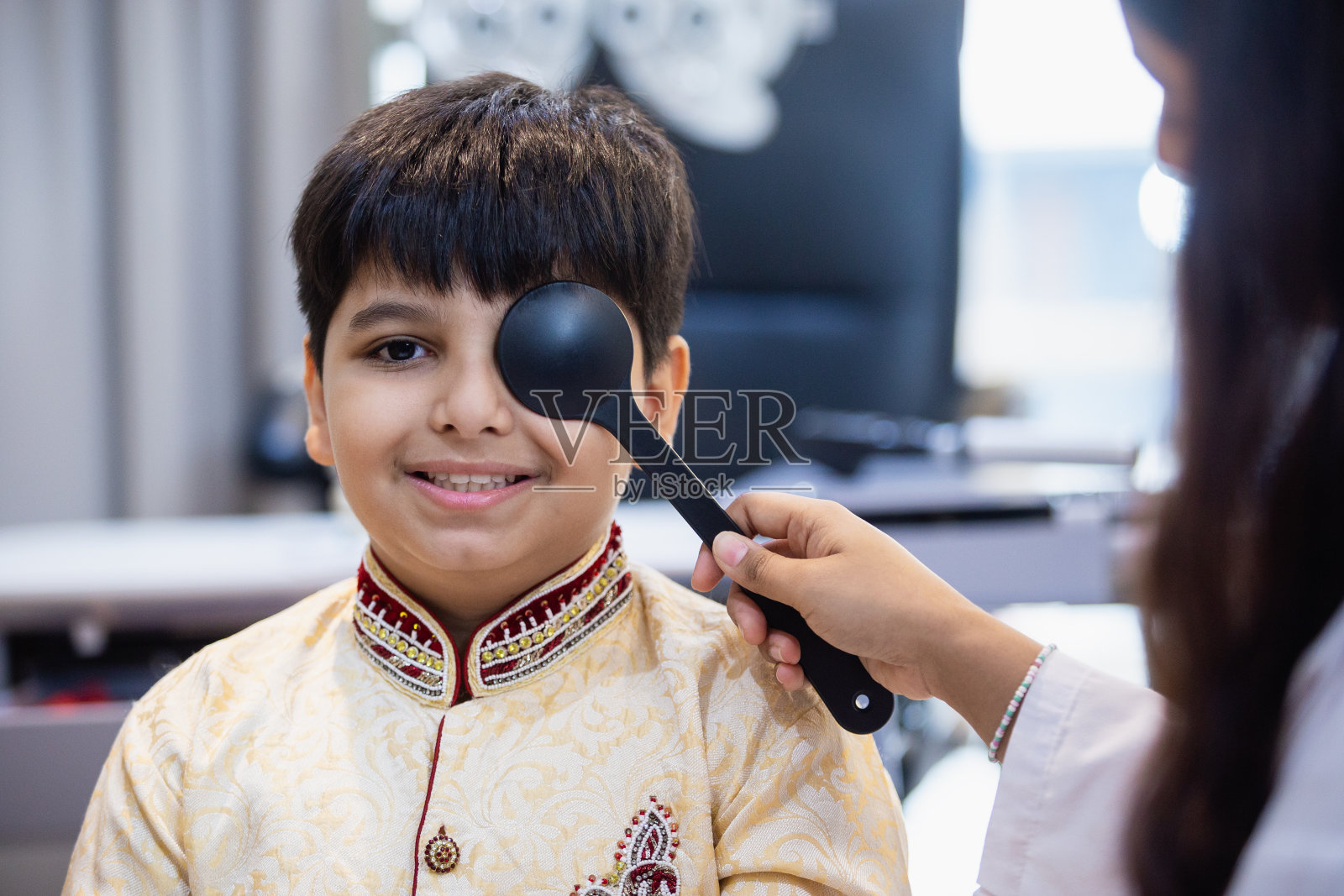 印度男孩检查视力检查视力远视检查眼科医院。医生用咬合器为印度男孩做眼科检查。照片摄影图片