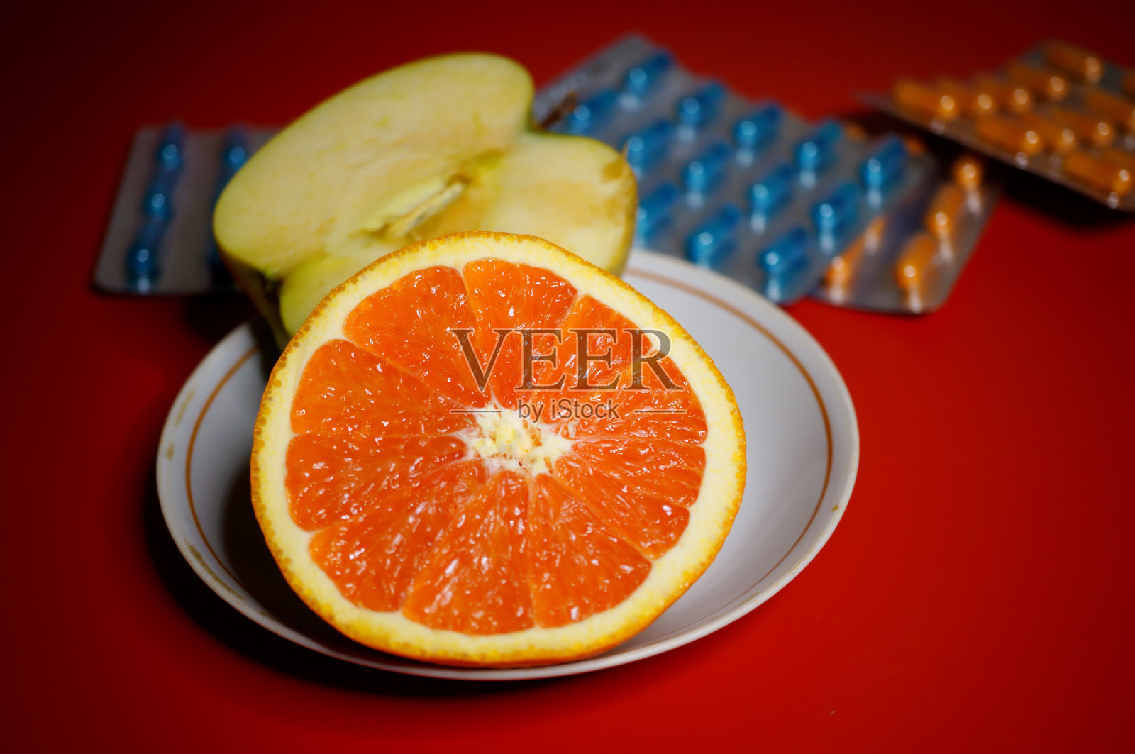 桌上有一包膳食补充剂和一个橙子。照片摄影图片