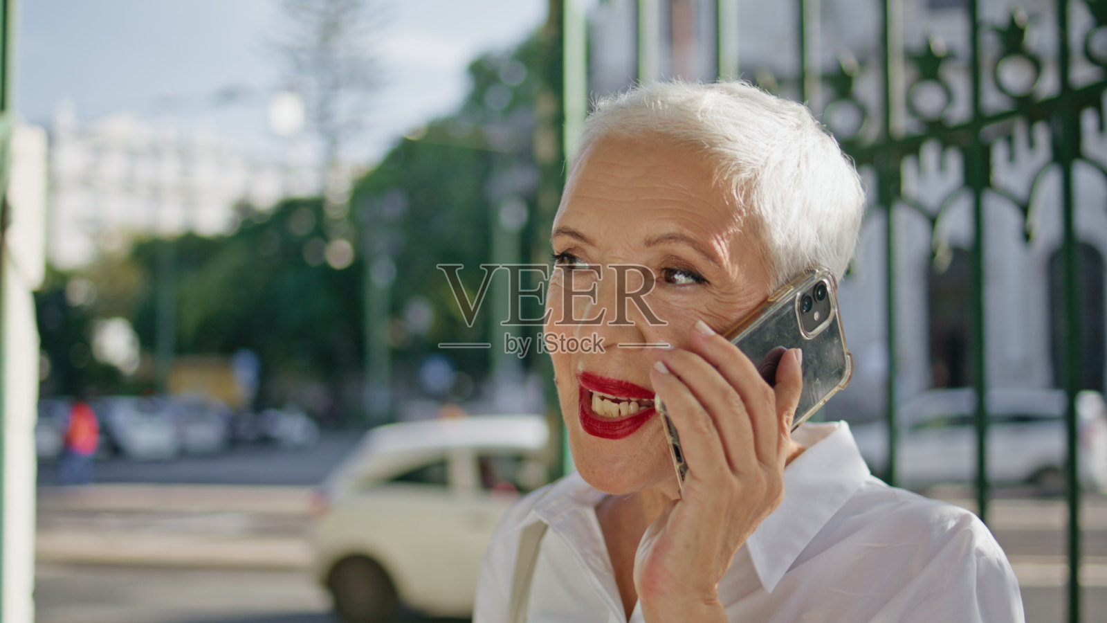 老年妇女在户外打电话的特写。阳光下快乐的退休者照片摄影图片